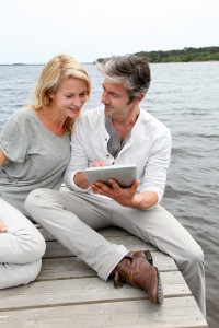 Couple sitting on boardwalk and using tablet